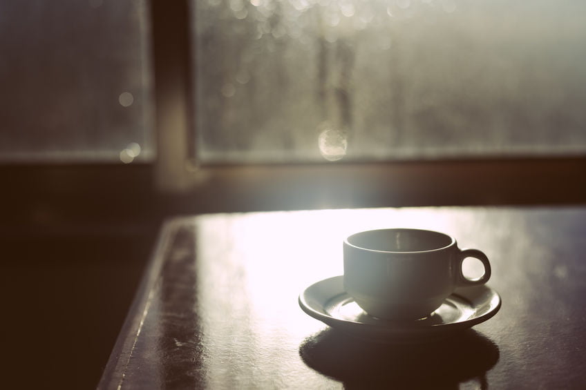 Cup of coffee over misted foggy glass window sill background